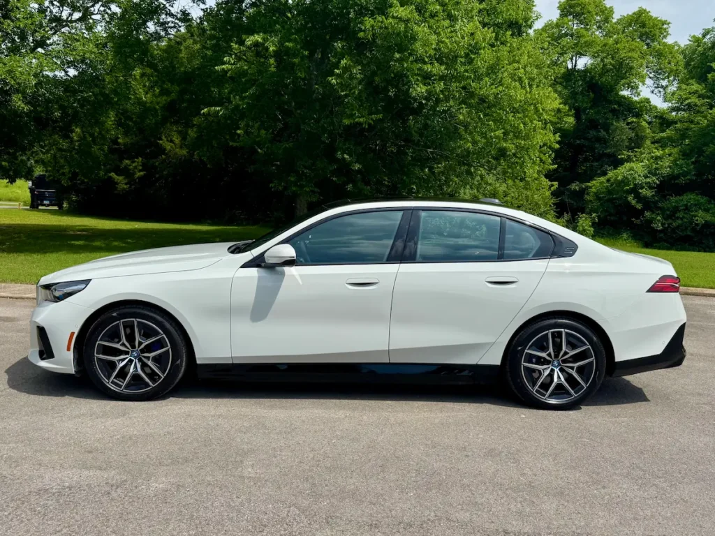 Side profile of a white 2024 BMW i5 eDrive40 showing its sleek body lines and aerodynamic shape.