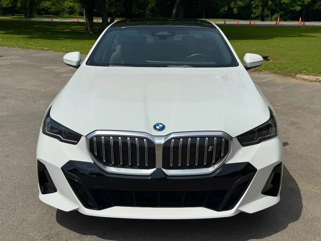 Front view of a white 2024 BMW i5 eDrive40 with its large kidney grille and slim LED headlights.