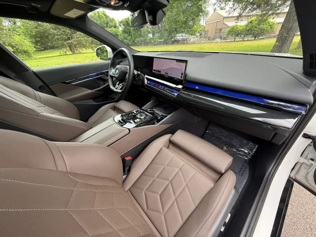 Interior of the 2024 BMW i5 with brown leather seats, curved digital display and modern dashboard.