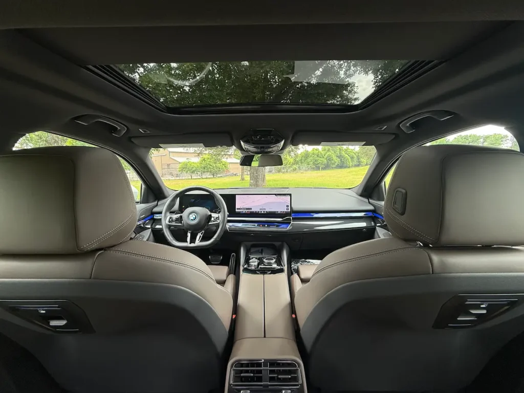 Interior view of the 2024 BMW i5 looking toward the dashboard and panoramic roof.
