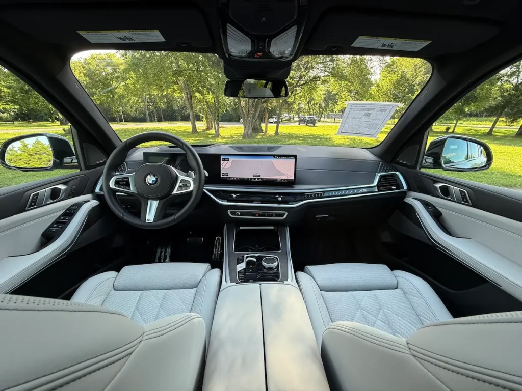 2024 BMW X5 dashboard with curved display and white leather interior