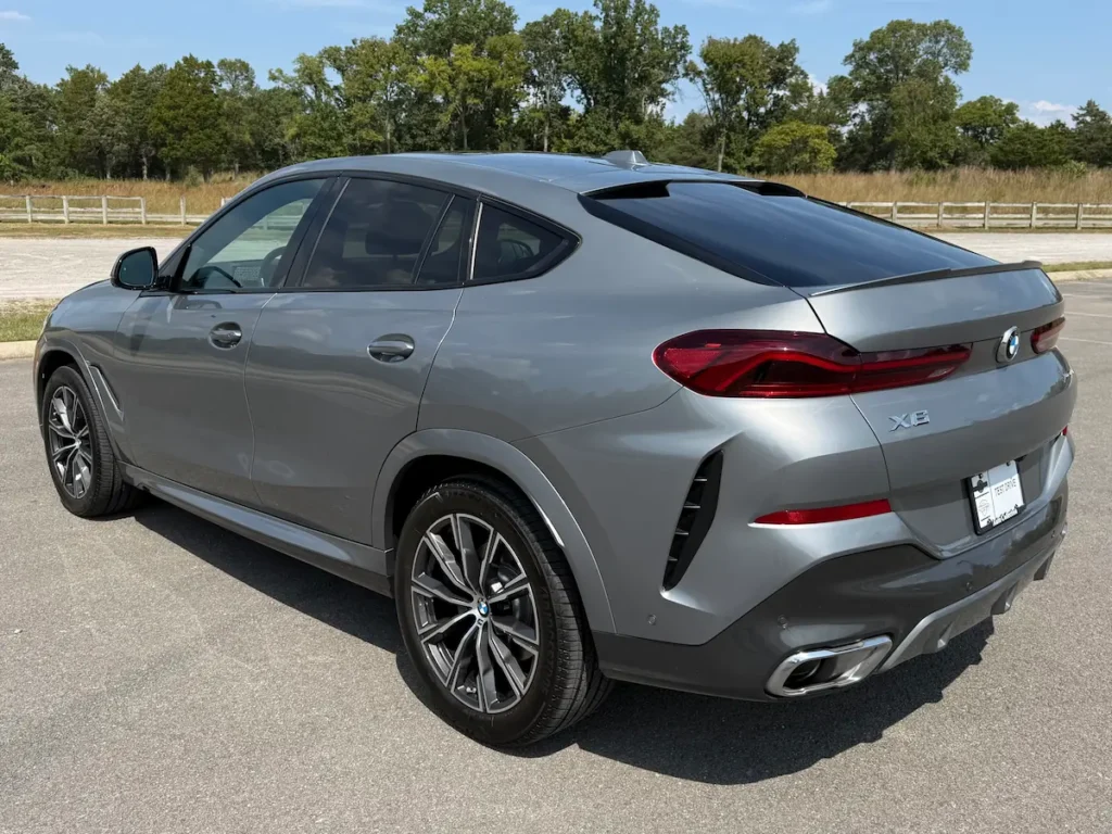 2024 BMW X6 grey exterior rear three-quarter view featuring LED tail lights and sloping roofline.