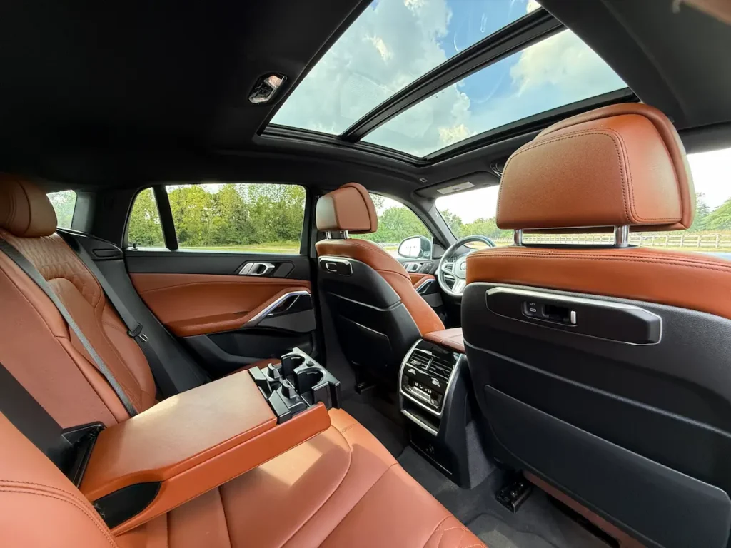 2024 BMW X6 interior second-row seating with brown leather upholstery and panoramic roof.