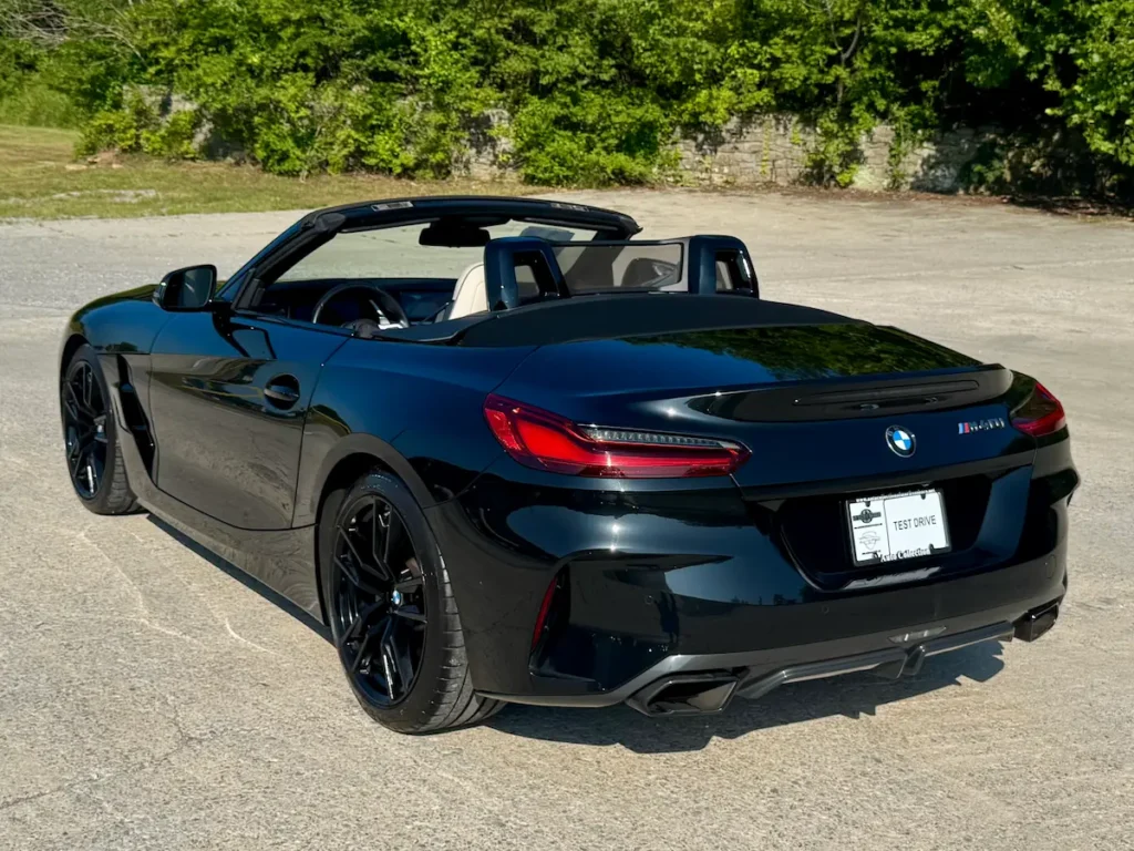 Rear three-quarter view of 2024 BMW Z4 black, emphasizing sporty rear design and dual exhaust.