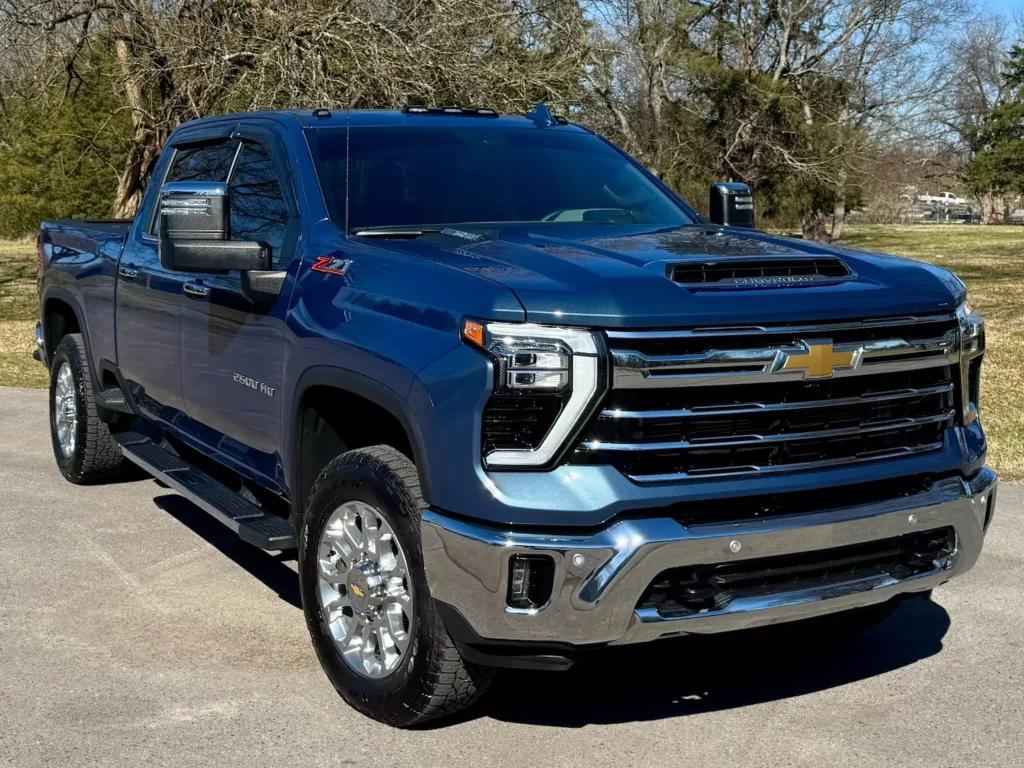 Front-side view of a 2024 Chevrolet Silverado 2500HD LTZ with Premium Package in blue featuring chrome assist steps and bold front grille.