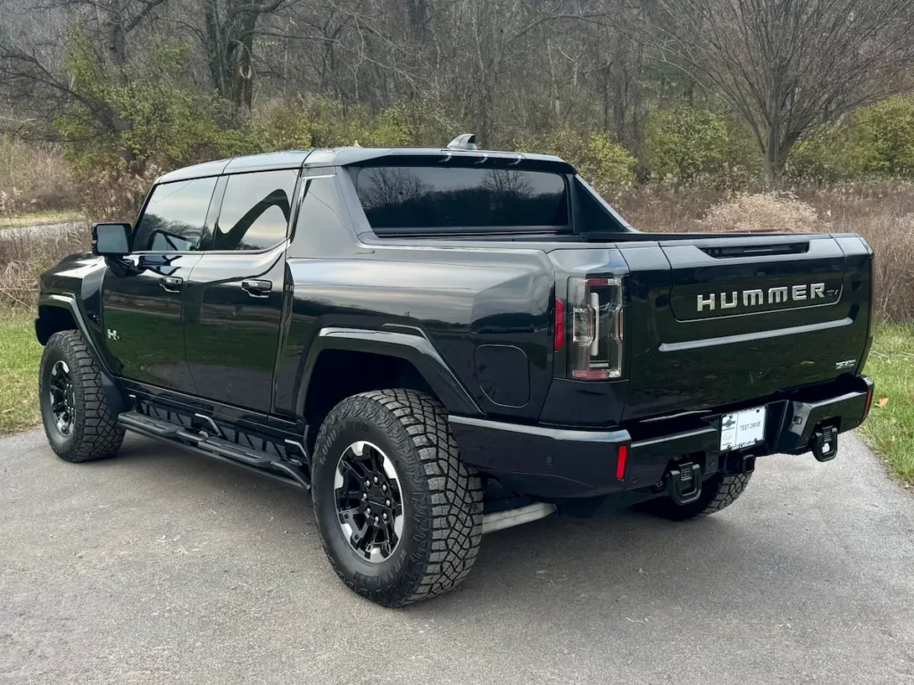 Rear exterior of a black 2024 GMC Hummer EV showcasing bed design and taillights.