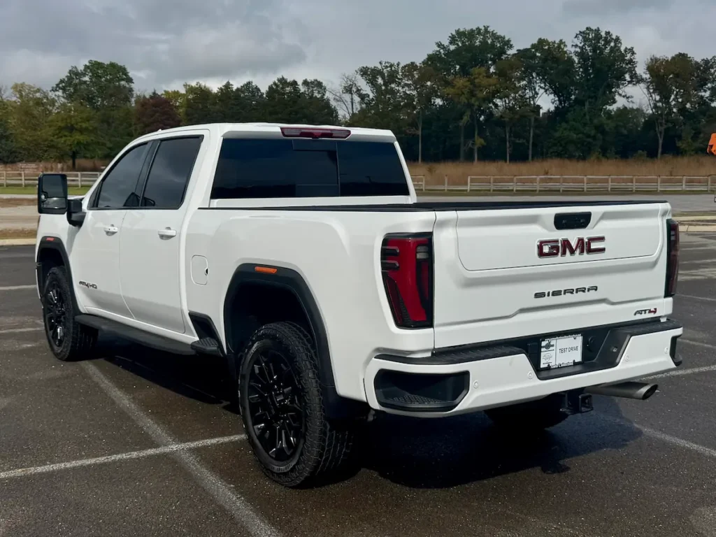 Rear exterior of a white 2024 GMC Sierra 2500 AT4 HD showing LED taillights and dual exhaust.