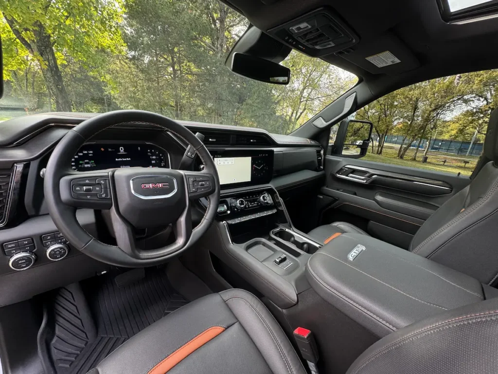Interior cockpit of a 2024 GMC Sierra 2500 AT4 HD featuring leather seats and digital displays.