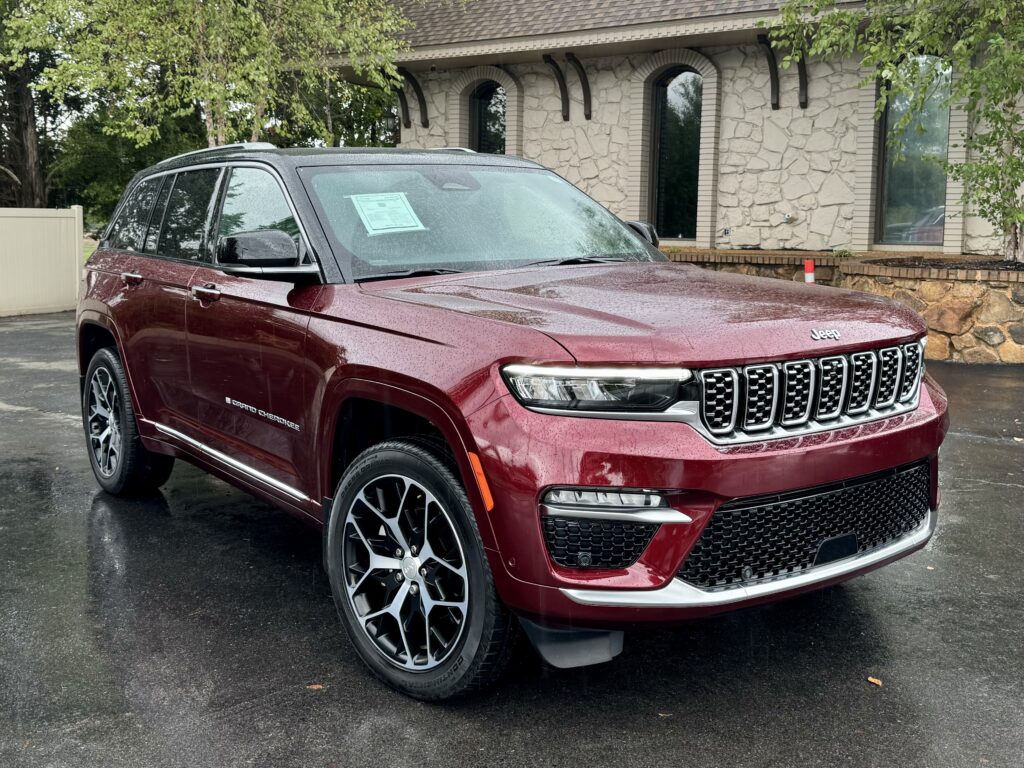 2024 Jeep Grand Cherokee Summit Reserve in burgundy with chrome grille, LED headlights, and premium alloy wheels.