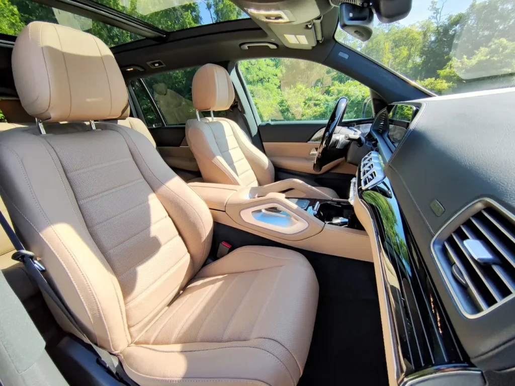 Front interior of 2024 Mercedes-Benz GLS 580 showcasing tan leather seats, black accents, and panoramic roof.