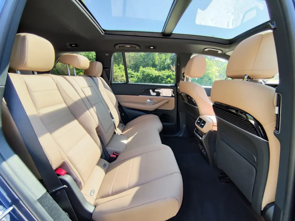 Second-row interior of 2024 Mercedes-Benz GLS 580 in tan leather with panoramic sunroof and ambient lighting.