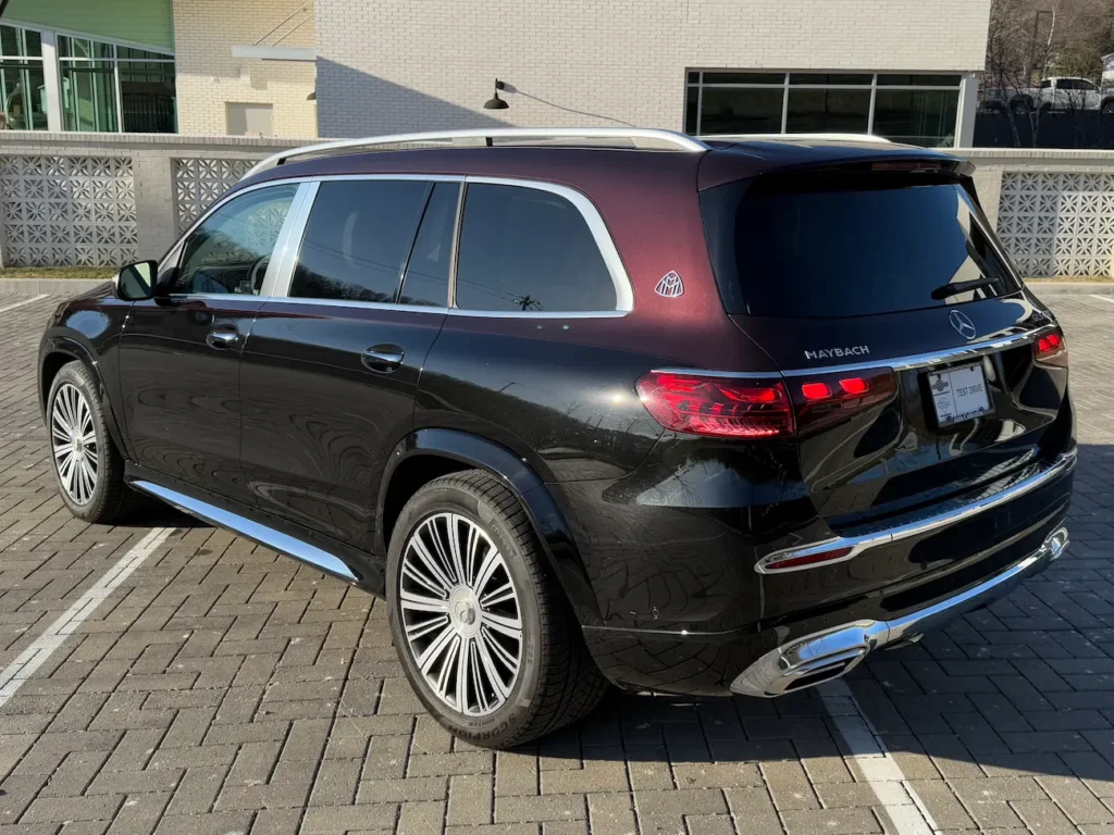 Rear exterior of 2024 Mercedes-Benz GLS 600 Maybach in two-tone black and maroon with chrome accents and Maybach emblem.