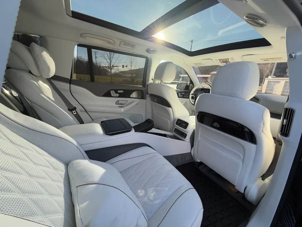 Rear interior of 2024 Mercedes-Benz GLS 600 Maybach with reclining white Nappa leather seats, panoramic sunroof, and Maybach badging.