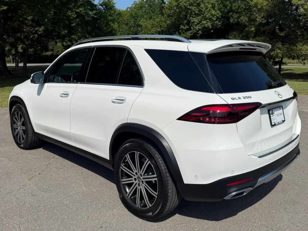 Rear three-quarter angle of 2024 Mercedes-Benz GLE 350 in white with chrome exhaust and black roof rails.