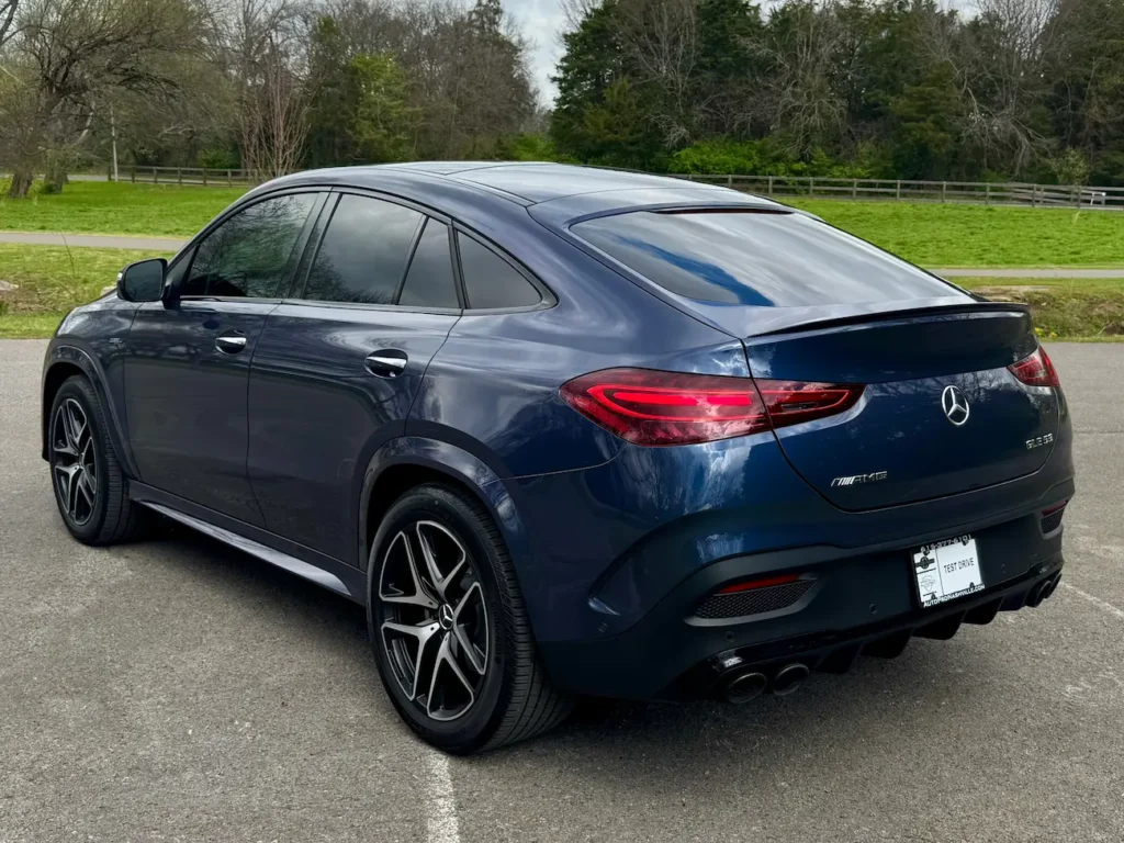 Rear angle of 2024 Mercedes-Benz GLE 53 AMG Coupe in blue showing quad exhaust and sloping roofline.