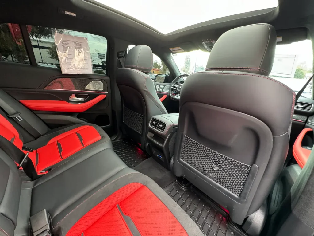 Rear seats of 2024 Mercedes-Benz GLE 63 S AMG Coupe with red and black leather upholstery and panoramic roof.