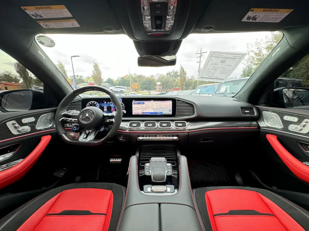 Interior front cabin of 2024 Mercedes-Benz GLE 63 S AMG Coupe featuring AMG steering wheel and carbon-fiber trim.