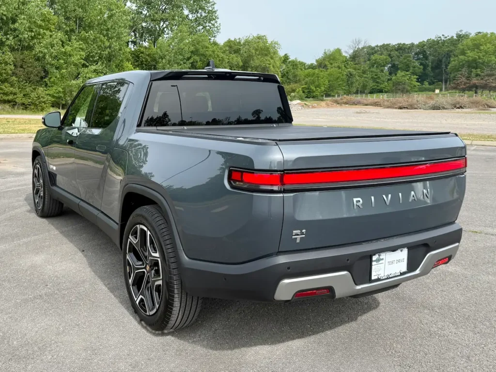 Rear three-quarter view of a gray 2024 Rivian R1T with closed tonneau cover