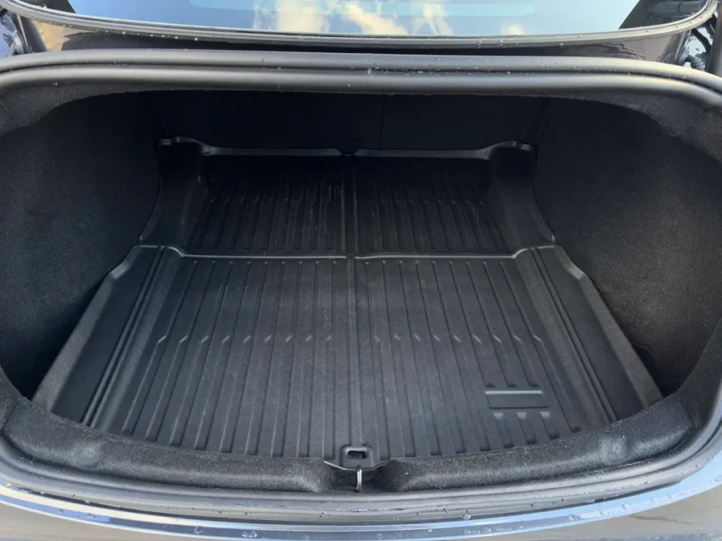 Open trunk of 2024 Tesla Model 3 showing large cargo bay with rubber mat liner.