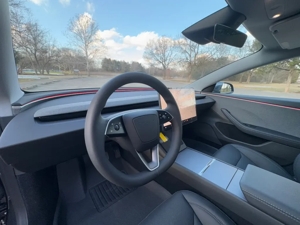 Interior of 2024 Tesla Model 3 showing minimalist dashboard, steering wheel, and central touchscreen.