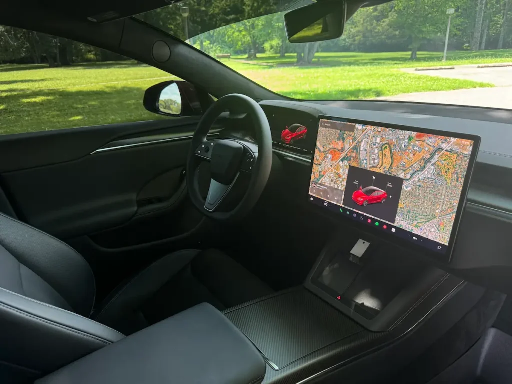 2024 Tesla Model S Plaid interior with large touchscreen, yoke-style steering, and digital controls