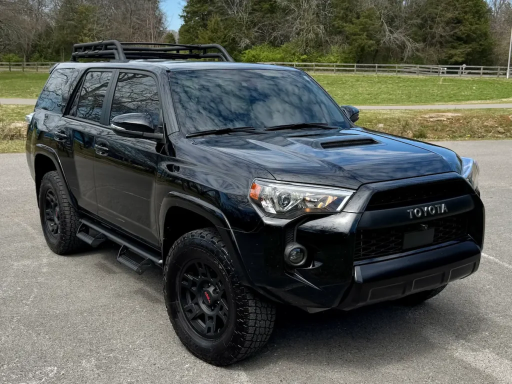 Black 2024 Toyota 4Runner shown from the front three-quarter angle with roof rack and black wheels.