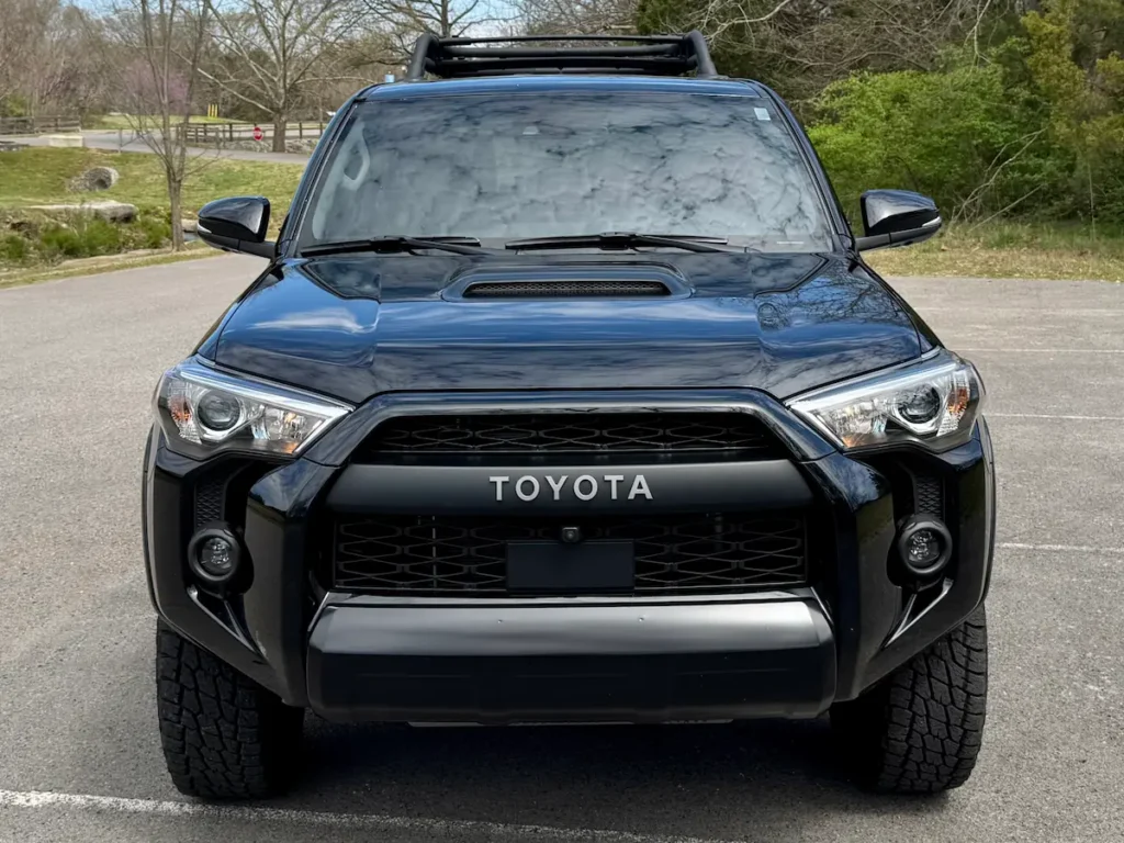 Front view of a black 2024 Toyota 4Runner with Toyota grille, hood scoop, and roof rack.