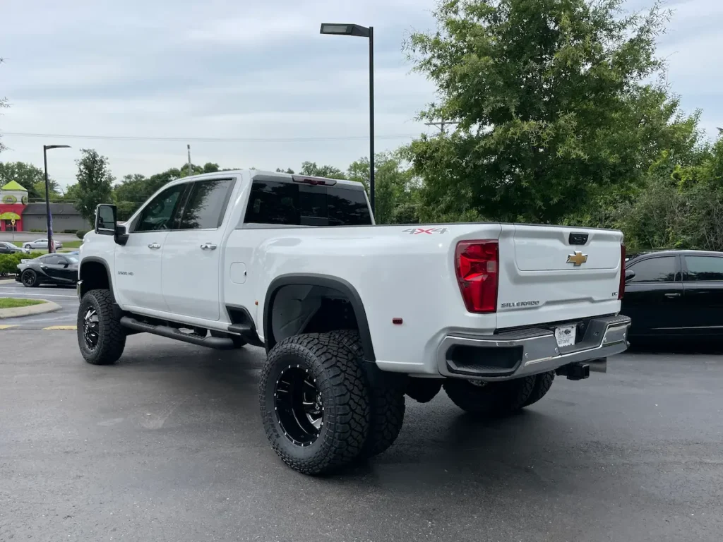 Rear three-quarter view of a lifted 2024 Silverado 3500HD LTZ DRW in white.