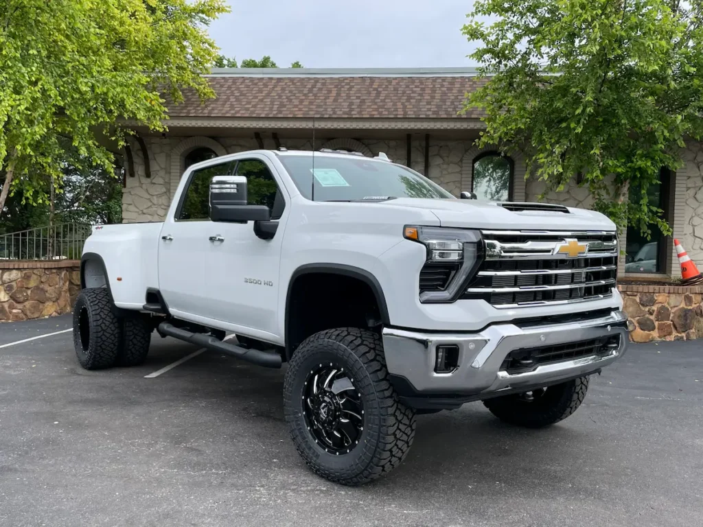 Three-quarter front angle of a white 2024 Silverado 3500HD LTZ dually with lifted setup.