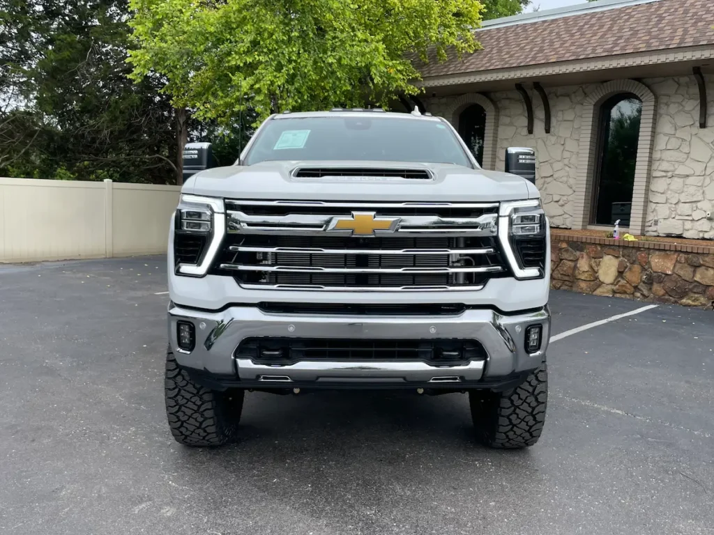 Front view of a lifted 2024 Chevrolet Silverado 3500HD LTZ dually in white with chrome grille.