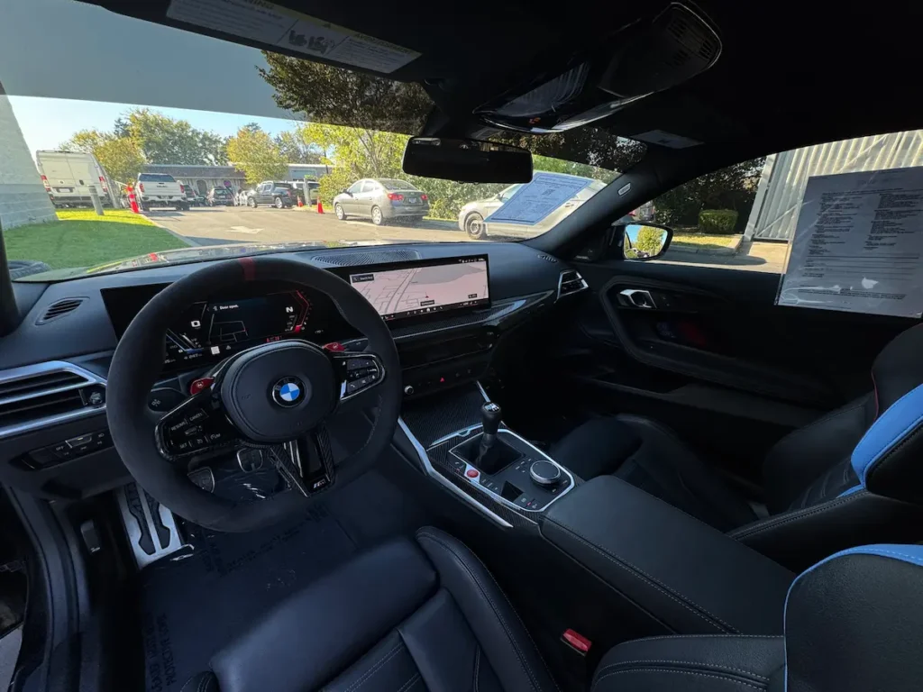 BMW M2 driver cockpit with digital display, manual transmission, and performance steering wheel