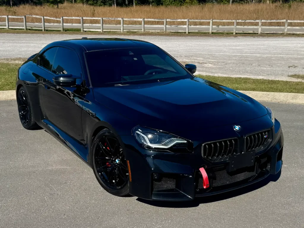 2025 BMW M2 black exterior front three-quarter view with aggressive performance styling.