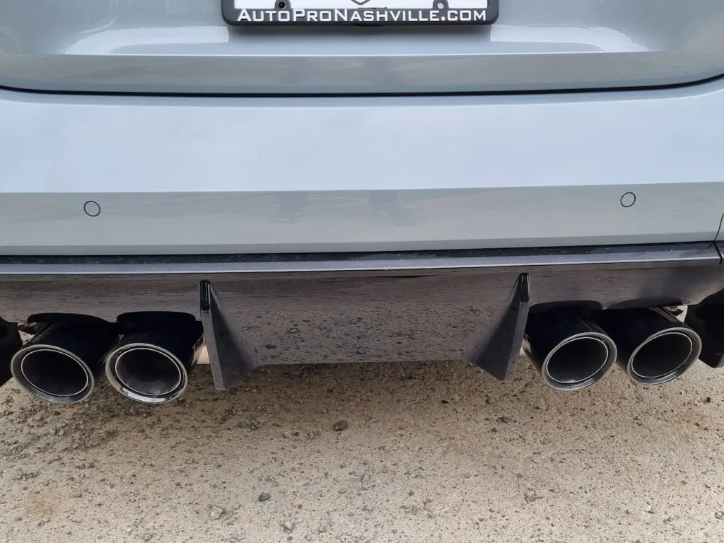 Close-up of quad exhaust system and carbon diffuser on 2025 BMW M4 Competition Convertible.