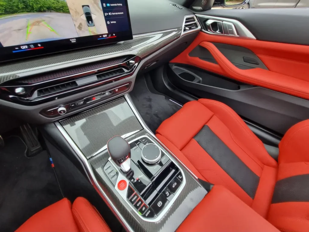Center console of 2025 BMW M4 Competition Convertible with carbon fiber trim and iDrive controls.