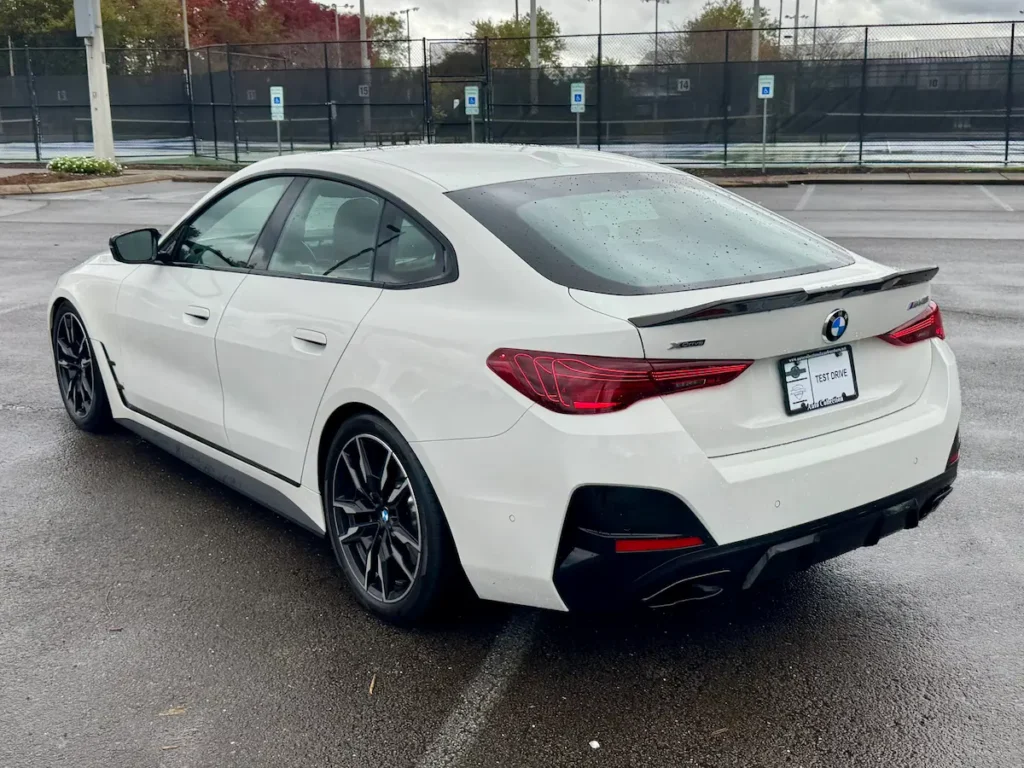 Rear angle of 2025 BMW M440i Gran Coupe with dual exhaust and sloping roofline.