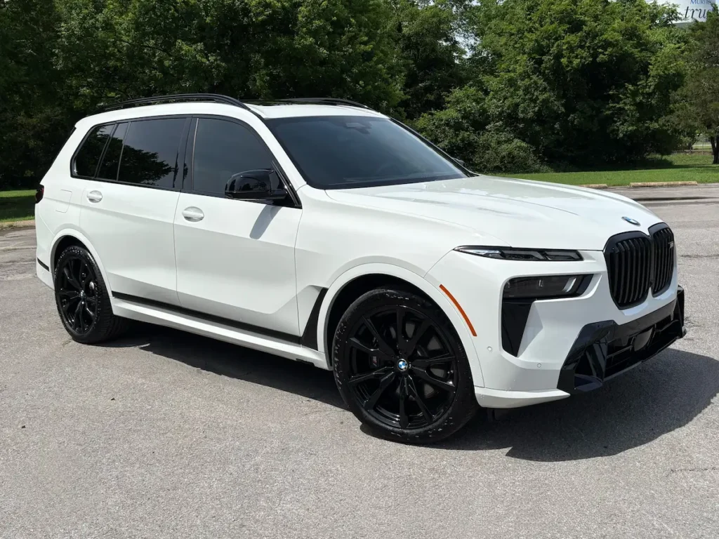 Front three-quarter view of a white 2025 BMW X7 M60i three-row luxury SUV