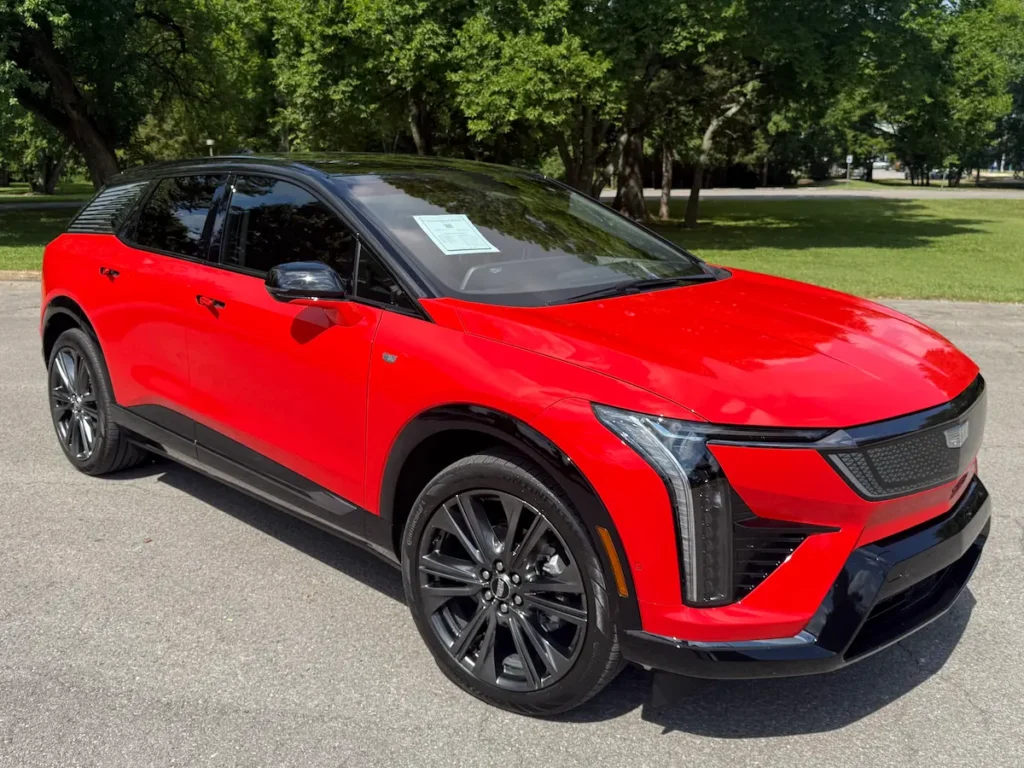 Front angle view of a red 2025 Cadillac Optiq featuring sharp LED headlights, dynamic grille design, and sporty EV body lines.