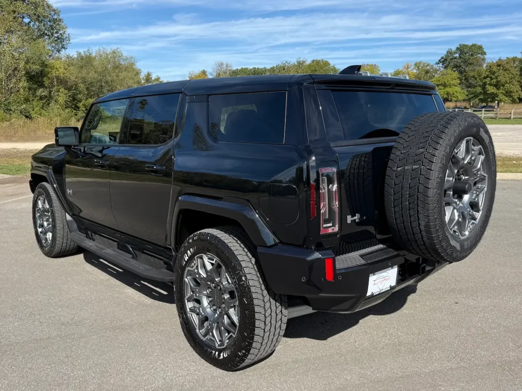 Rear exterior of a black 2025 GMC Hummer EV 3X with full-size spare tire mounted on the back.
