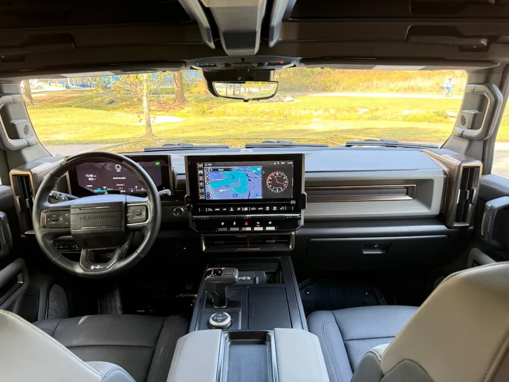 Front cockpit of a 2025 GMC Hummer EV 3X with dual digital screens and rugged dashboard.