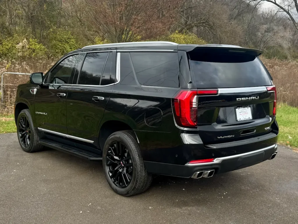 Rear exterior of a black 2025 GMC Yukon Denali showcasing taillights and dual exhaust.