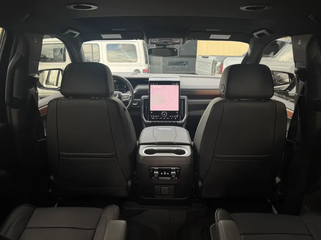Interior view from second row showing the 2025 GMC Yukon Denali’s touchscreen and cabin layout.
