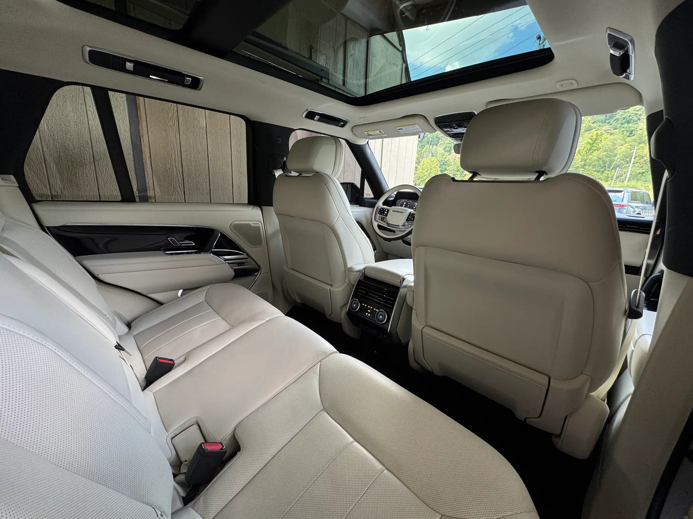 2025 Range Rover P530 SE rear cabin with light leather seats, a folding center armrest and panoramic glass roof.