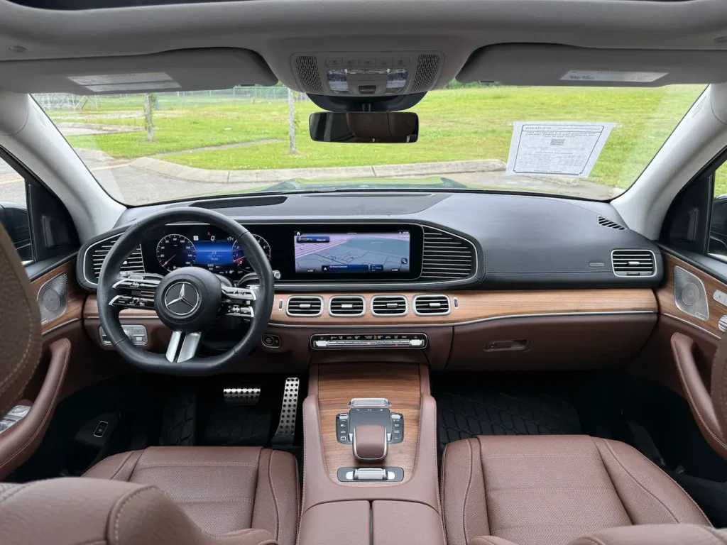 Front cabin of 2025 Mercedes-Benz GLS 450 with dual displays, wood trim, and Nappa leather seating.