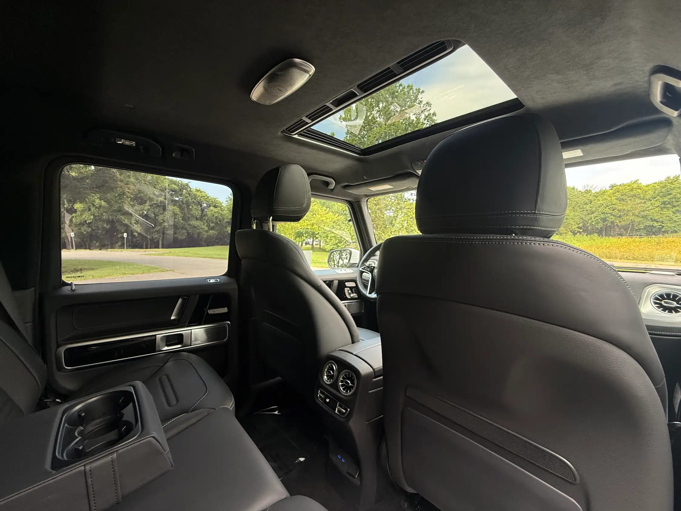 2025 Mercedes-Benz G 550 rear cabin with black leather seating, a lowered center armrest, rear air vents and sunroof.