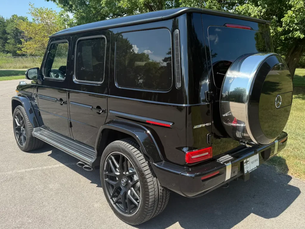 2025 Mercedes-Benz G63 AMG rear three-quarter view in black with AMG wheels and side exhaust