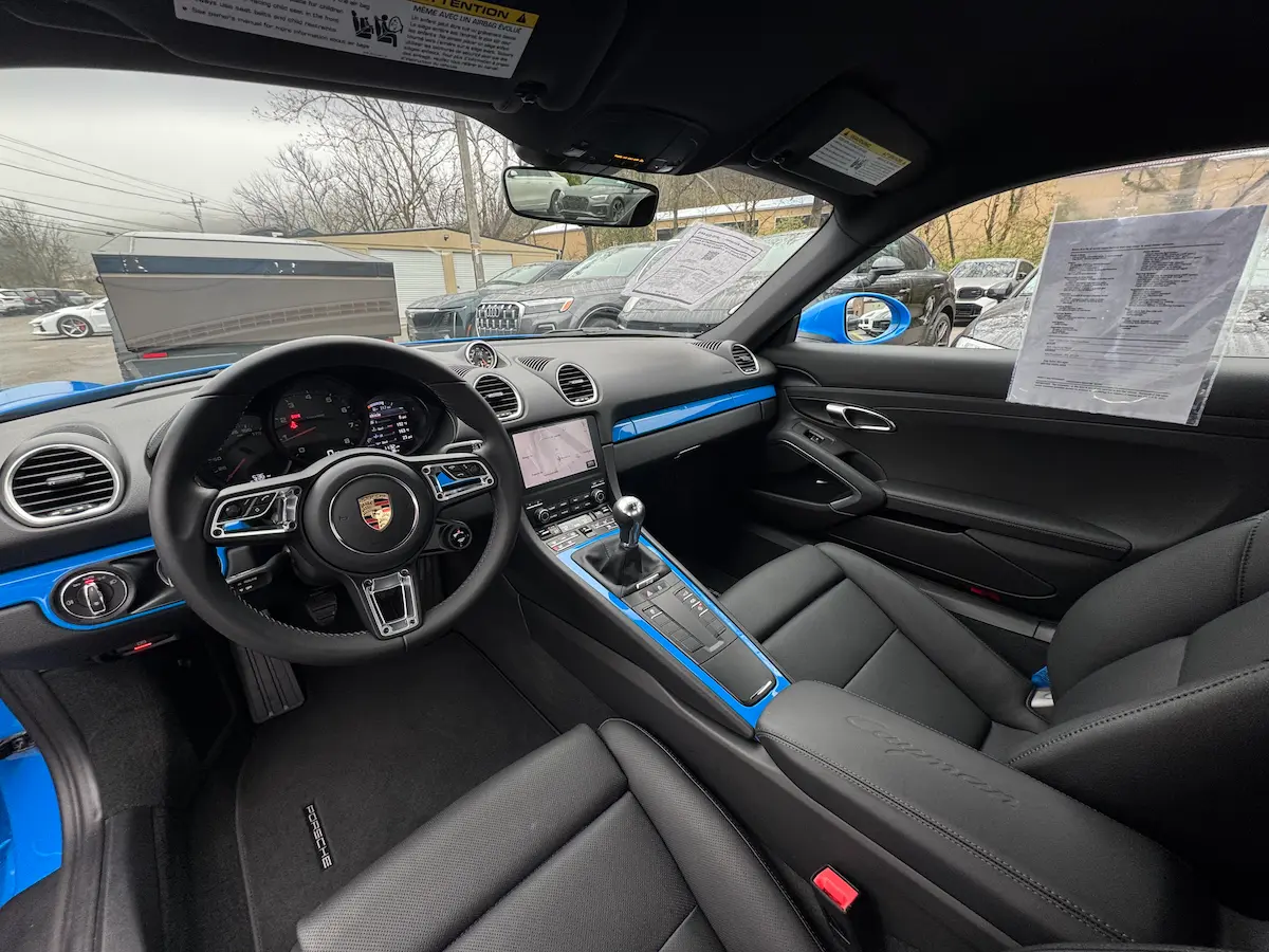 Black interior of a blue 2025 Porsche 718 Cayman with manual transmission