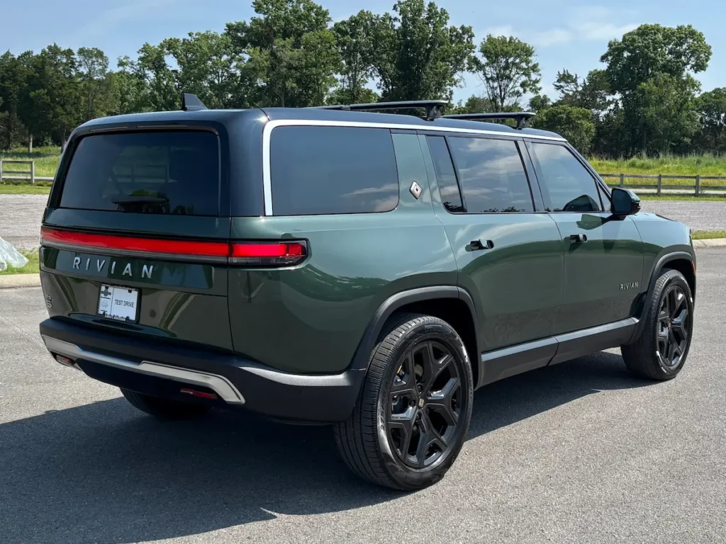 Rear three-quarter view of a green 2025 Rivian R1S electric SUV