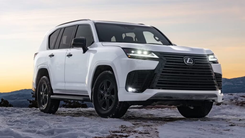 Front exterior view of a 2025 Lexus LX 600 Premium SUV with a bold spindle grille and LED headlights parked in snow.