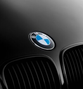 Close-up photo of a black BMW hood with a chrome BMW logo in the center.