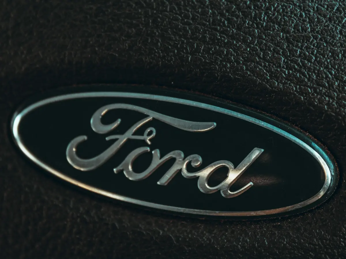 Close-up of the classic Ford logo emblem on black textured background.